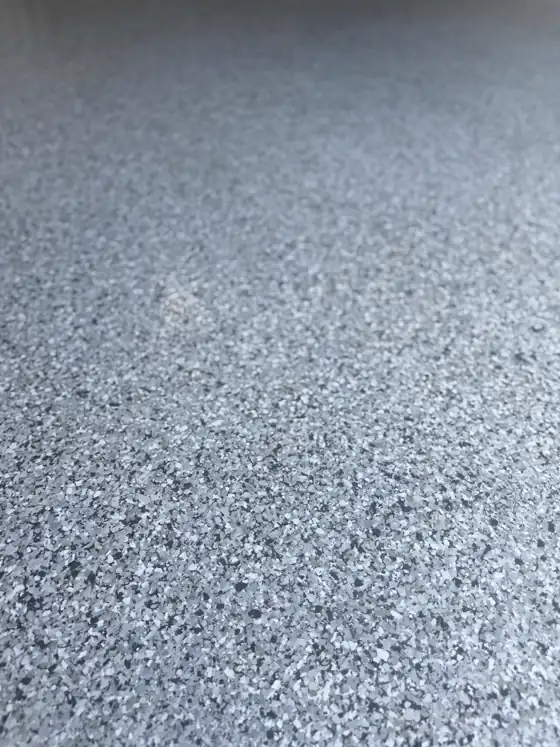 Close detail of grey and white flake chips under a clear topcoat