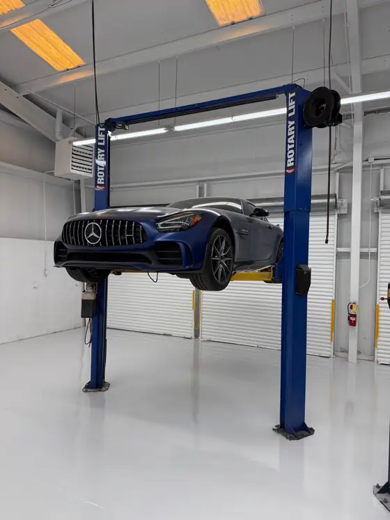 A car raised on a lift above a white epoxy shop floor